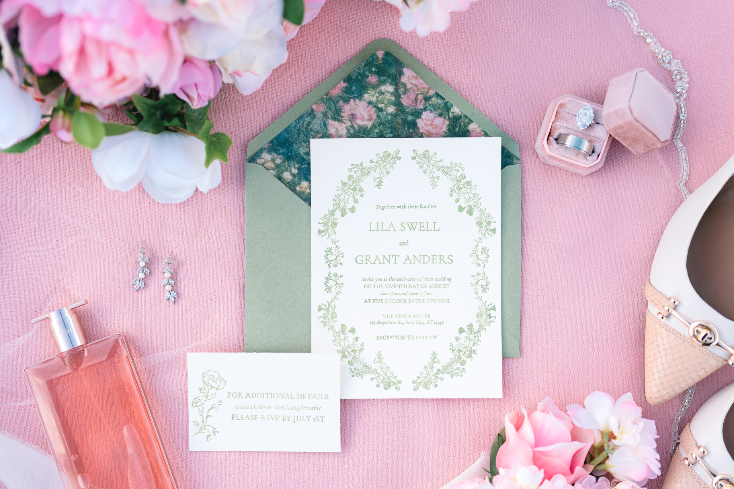 Wedding rings styled on invitation suite with blush ribbon and floral accents in Lafayette, Louisiana